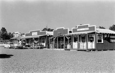 an old black and white photo of a small store with cars parked in front of it