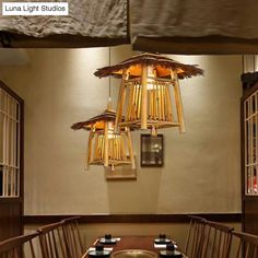 a wooden table topped with lots of plates and cups next to a light fixture hanging from the ceiling