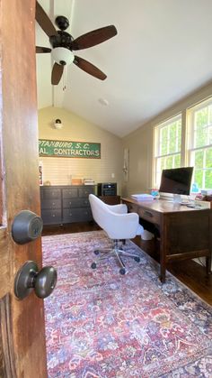 a room with a rug, desk and ceiling fan