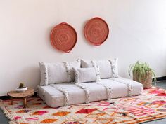 a white couch sitting on top of a rug next to two red and orange baskets