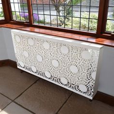 a white radiator sitting next to a window on top of a tiled floor