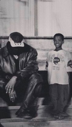 two young boys sitting on a bench in front of a man wearing a leather jacket