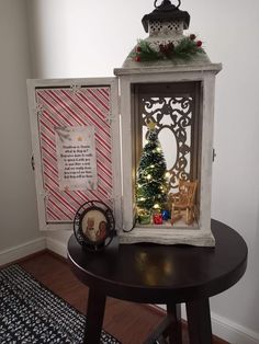 a small christmas tree sits in an old window frame on top of a round table