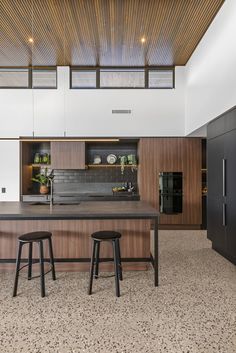 an open kitchen with two stools in front of the counter and cabinets on both sides