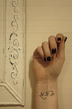 a woman's hand with a small tattoo on her left wrist and the word love written in cursive writing