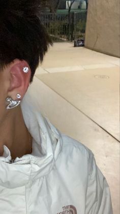 a close up of a person with ear piercings on their ears and wearing a white jacket