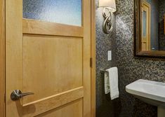 a bathroom with a sink and mirror next to a wooden door that has a glass paneled window