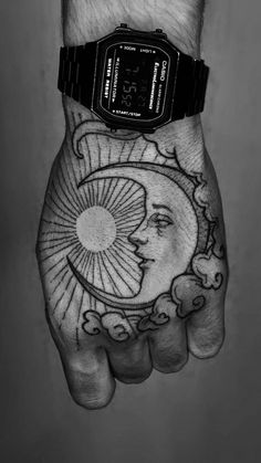 a man's hand with a sun and moon tattoo design on it, while the other hand is holding a watch