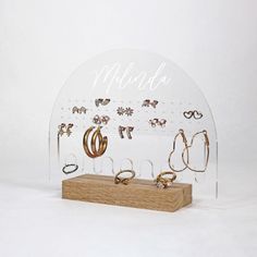 a clear acrylic display with lots of rings and earrings hanging on the wall