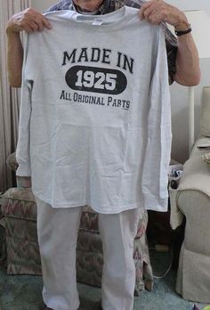 an older man holding up a made in 1953 t - shirt