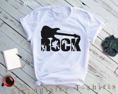 "Rock and Guitar Shirt. Rock and Roll Music Band Shirt. Rock Music Shirt. Rock and Roll Shirt. Music Teacher Gift. Rock Music Lover Gift... Check Out for Other Rock Music Shirts  https://www.etsy.com/shop/StrangistryTshirts?search_query=rock ----- How To Order ----- 1-) Please, check and review all the photos. 2-) Choose your t-shirt size and color. *Different styles of shirts may have different shades of same color choice due to different manufacturer brands. *For this reason, we recommend you to match shirts from the same styles if you want precisely matching colors (ex. Unisex, V-necks, Toddler, etc.). 3-) Click add to cart. You can go back to add more shirts. 4-)Click \"Proceed to check out\". 5-)When you check out, you can add a note to seller for any request. ----- Unisex Shirts ---- White Rocker T-shirt With Graphic Print, White Rocker Graphic Print T-shirt, White Rocker Style Graphic T-shirt, White Crew Neck Rock T-shirt, White Rock And Roll T-shirt For Concert, Rock And Roll White Top With Screen Print, White Rock And Roll Top With Screen Print, White Rock And Roll Screen Printed Top, White Short Sleeve Rock T-shirt