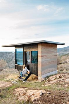 a man sitting on the side of a small wooden structure with his feet in the ground