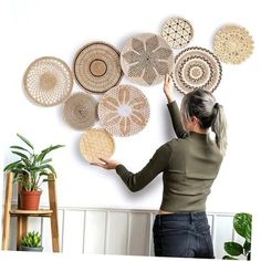 a woman placing woven baskets on the wall