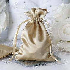 a gold satin bag sitting on top of a table next to white flowers and a pair of scissors