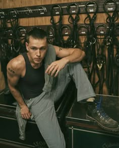 a man sitting on top of a suitcase in a room filled with lots of shoes