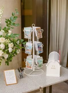 there is a vase with white flowers and cards on the table next to an easel