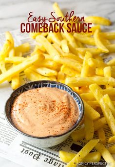 some french fries are next to a sauce in a small bowl on top of newspaper