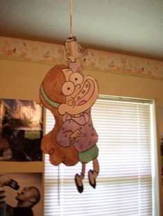 a child's mobile hanging from the ceiling in front of a window with pictures on it