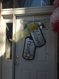 two door hangers that say welcome home and have yellow bows on the front door