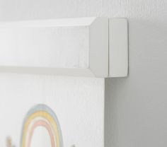 a close up of a white wall with a rainbow painted on it and two hooks attached to the wall