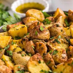 potatoes with herbs and seasoning in a bowl next to some parsley on the side