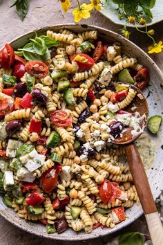 a bowl filled with pasta salad and a wooden spoon