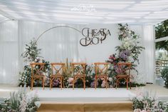 a wedding setup with chairs and flowers on the stage