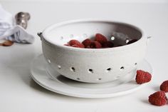 some raspberries are in a bowl on a plate