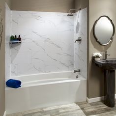 a white bath tub sitting next to a sink in a bathroom under a round mirror