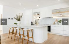 a kitchen with white counters and stools next to an island in the middle of the room