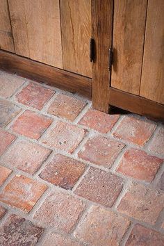 an old brick floor with wooden cabinets in the background