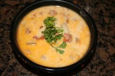 a black bowl filled with soup and garnished with parsley