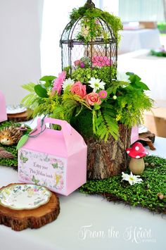 there is a birdcage with flowers in it on the table next to other items