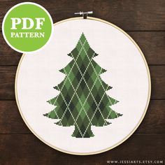 a cross stitch christmas tree on a wooden background with the text free pattern below it