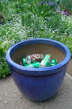 a blue planter filled with lots of empty beer cans in the middle of a garden