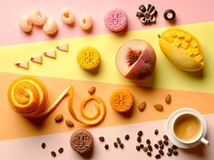 an assortment of fruits and pastries are arranged on a multicolored background with coffee