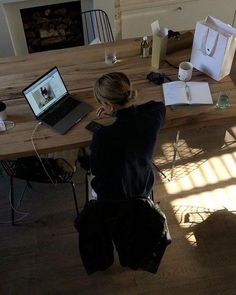 a woman sitting at a wooden table using a laptop computer