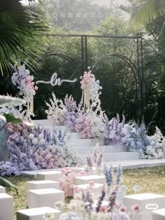 an outdoor ceremony setup with flowers and greenery on the ground, surrounded by white cubes