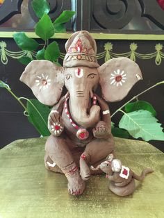 an elephant figurine sitting on top of a table next to a baby elephant