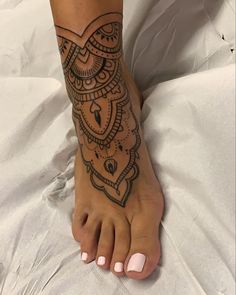 a woman's foot with an intricate tattoo design on the top and bottom of it