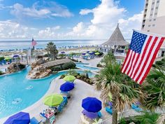 an outdoor pool with umbrellas and chairs next to the beach