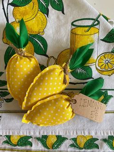 two lemons on a yellow and white table cloth with a tag hanging from it