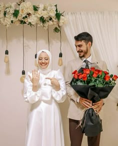 a man and woman standing next to each other with flowers in front of their faces