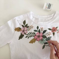 someone is painting flowers on a white t - shirt with red pencils and scissors