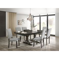 a dining room table with grey chairs and a chandelier hanging from the ceiling