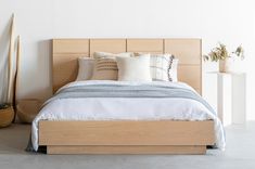 a bed with white sheets and pillows in a room next to two planters on the wall