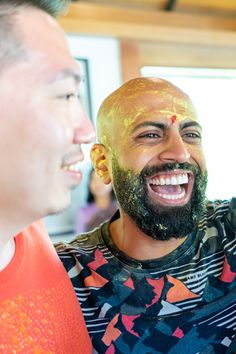 two men are laughing and having fun with each other while one man has his face painted gold