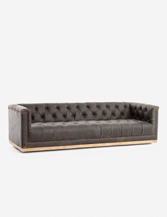 a black leather couch with wooden legs and buttons on the back, in front of a white background