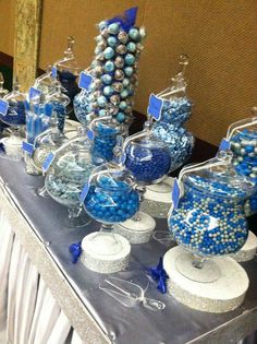 a table topped with lots of blue and white candy covered in gummy balls on top of glass vases