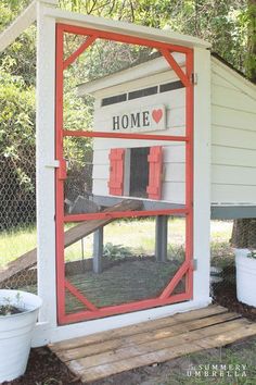 a chicken coop with red shutters on the side and a sign that says home